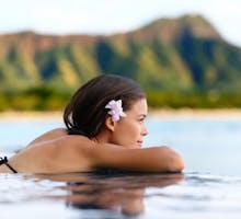 Infinity pool resort woman relaxing at sunset overlooking Waikiki beach