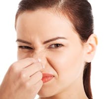 Portrait of a young woman holding her nose because of a bad smell